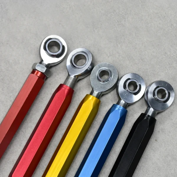 Close-up of adjustable rod end linkages in red, yellow, blue, and black for suspension systems.