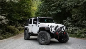 Jeep Wrangler Rubicon off-road vehicle parked on a gravel path surrounded by trees.
