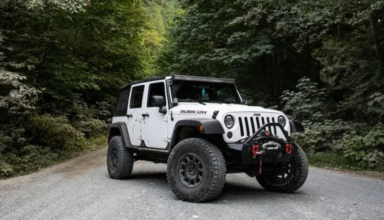 Jeep Wrangler Rubicon off-road vehicle parked on a gravel path surrounded by trees.