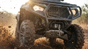 ATV riding through a harsh off-road environment with rocky terrain and mud.