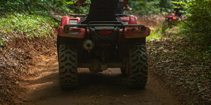 Rider on an ATV navigating a rough trail.
