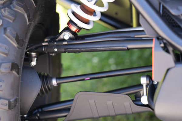 Close-up of an off-road vehicle suspension showing a coilover shock and suspension arms behind the tire edge.