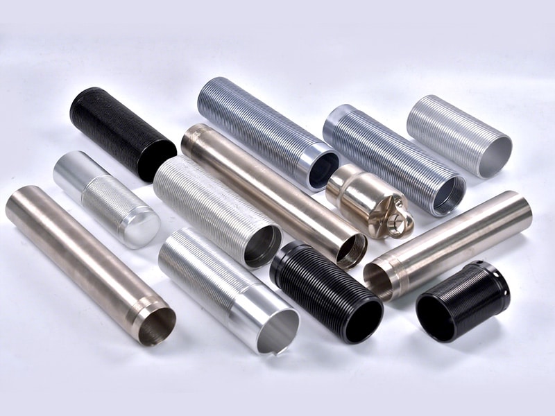 Assorted metal tubes and sleeves in different diameters and finishes on a light surface.
