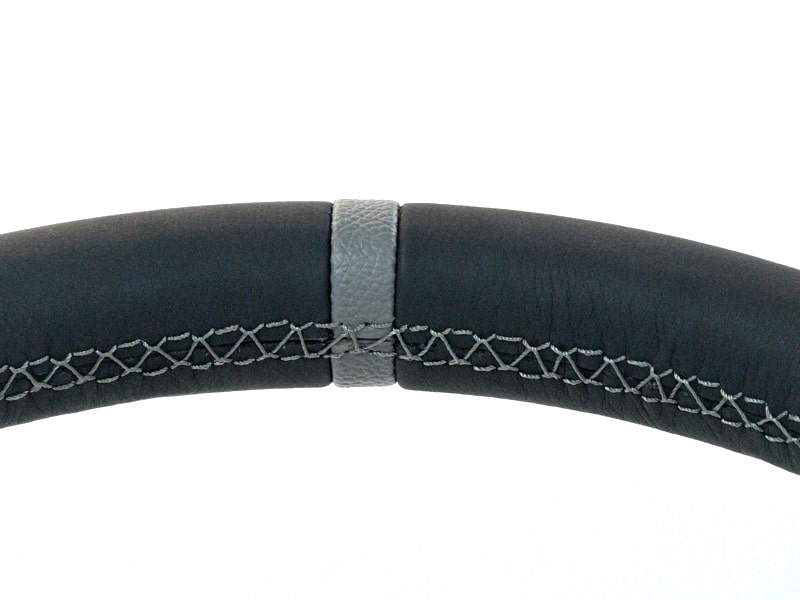 Close-up of black leather steering wheel with a gray stitched seam running across the center with visible cross-stitching on the sides.