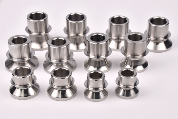 Shiny stainless steel cylindrical spacers arranged in rows on a white background